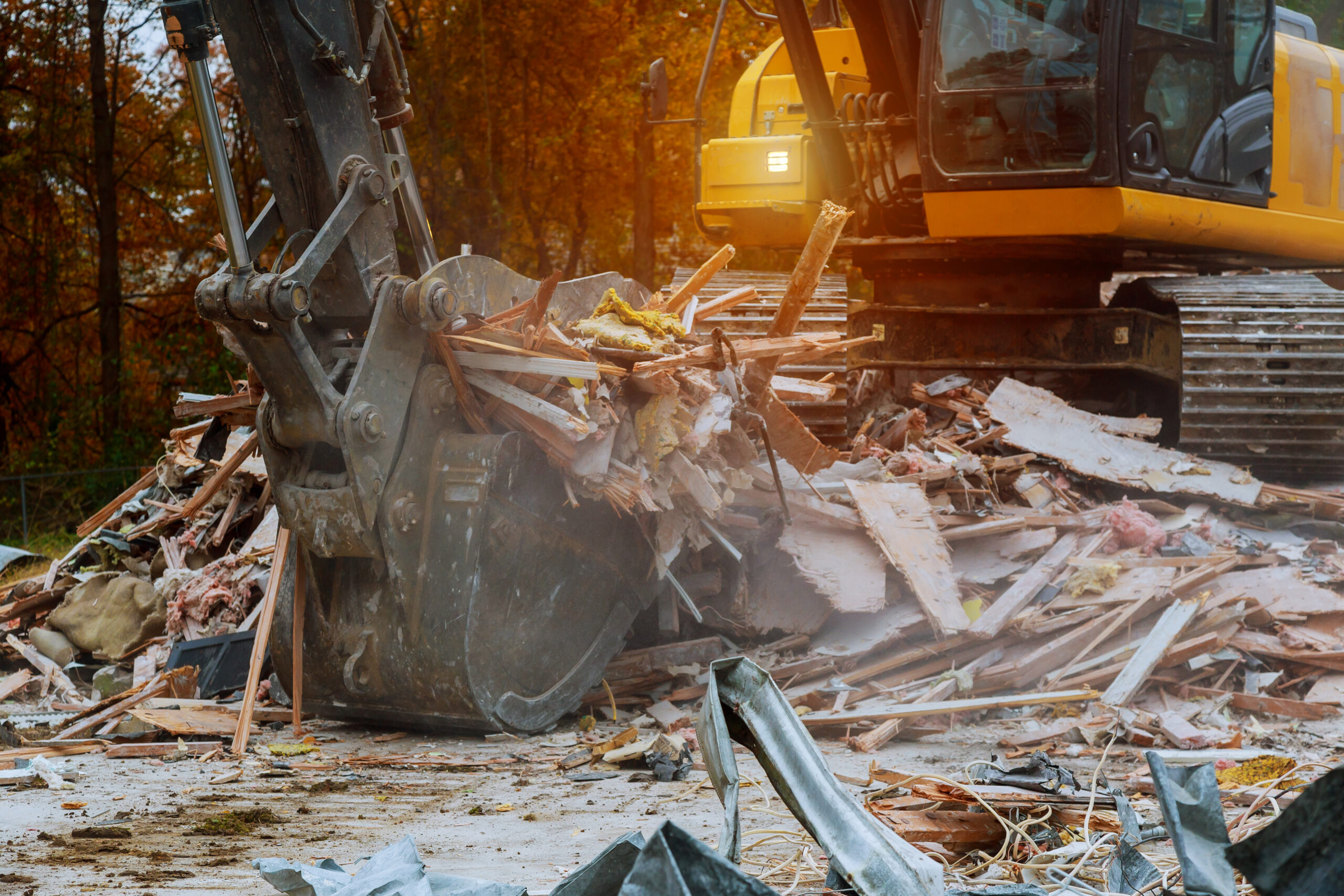 old house being excavator demolished by a large backhoe wooden planks and rubble and the ruins